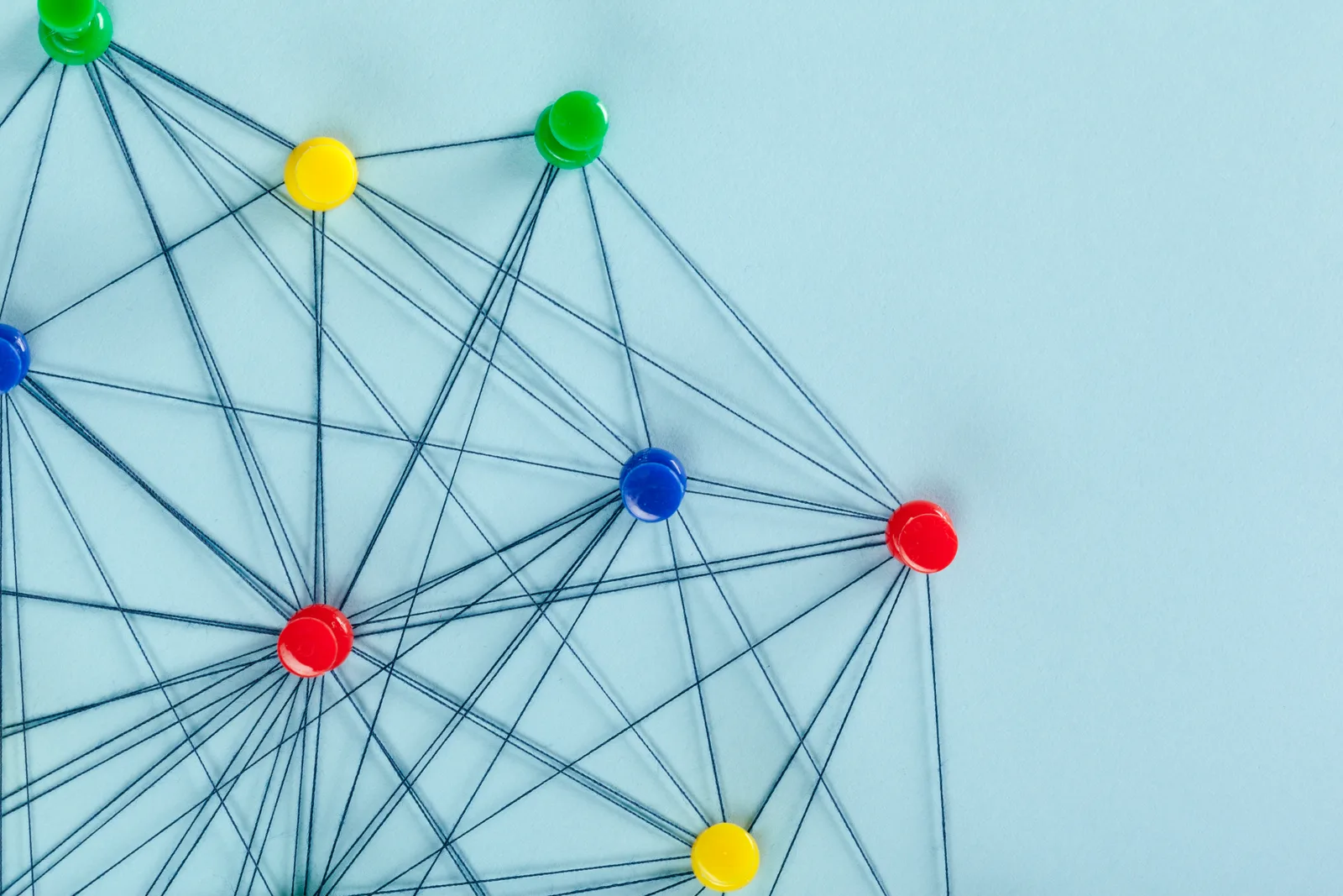 Coloured push pins joined by threads into a network, like an automated workflow
