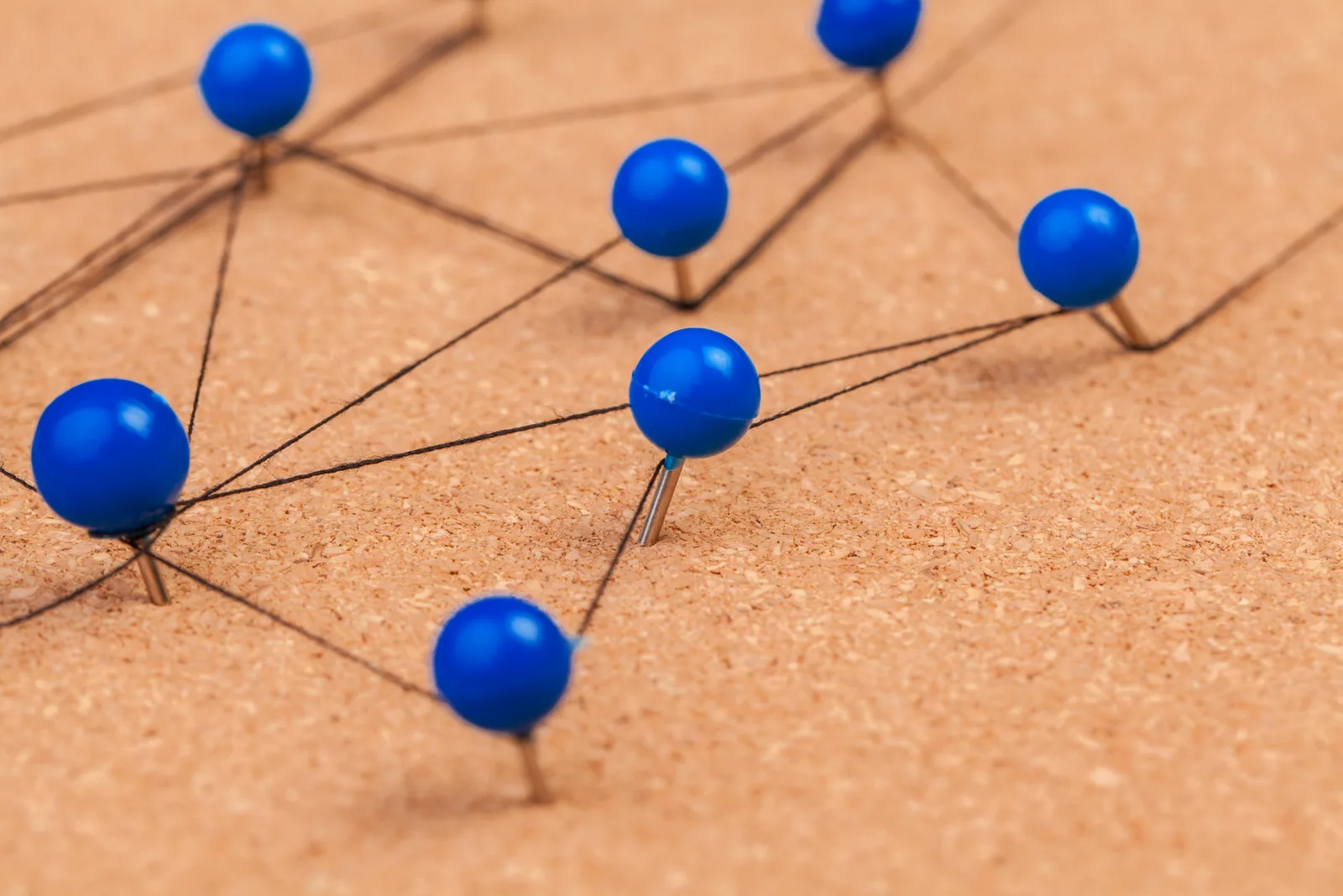 Blue pins on a cork board connected by thread in a chain, like a pipeline of steps