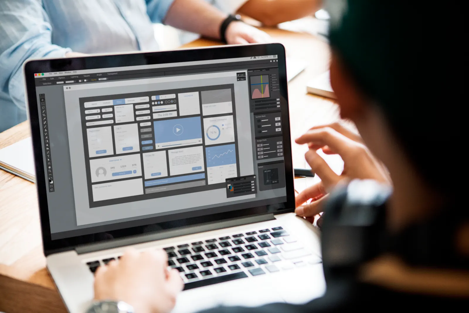 A small team working together around a laptop showing a dashboard design